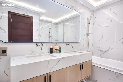 a bathroom with white marble walls and a large mirror at bnbmehomes - Tiara Residence in Dubai