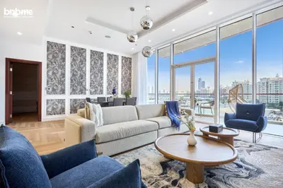 a living room with a couch and chairs and windows at bnbmehomes - Tiara Residence in Dubai