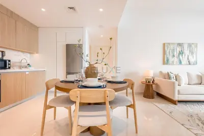a kitchen and living room with a table and chairs at Prime Waterfront Location with Stunning Palm Jumeirah Views, Close to Dubai Top Attractions - Beach Vista Tower 2, Emaar Beachfront by Deluxe Holiday Homes in Dubai