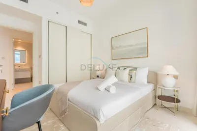 a bedroom with a white bed and a blue chair at Prime Waterfront Location with Stunning Palm Jumeirah Views, Close to Dubai Top Attractions - Beach Vista Tower 2, Emaar Beachfront by Deluxe Holiday Homes in Dubai