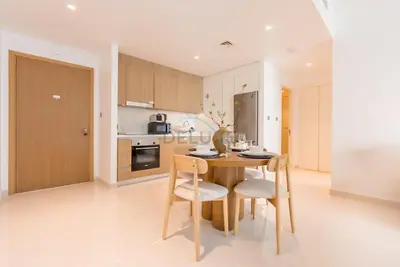 a kitchen and dining room with a wooden table and chairs at Prime Waterfront Location with Stunning Palm Jumeirah Views, Close to Dubai Top Attractions - Beach Vista Tower 2, Emaar Beachfront by Deluxe Holiday Homes in Dubai