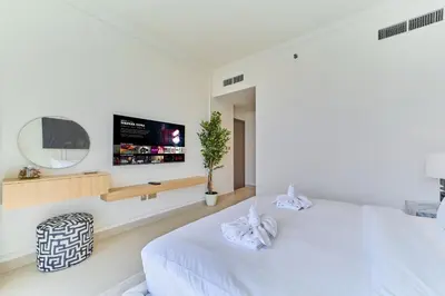a bedroom with two white beds and a flat screen tv at Elegant Beachfront 2BR at Palace Beach Residence in Dubai