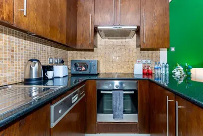 a kitchen with wooden cabinets and a stainless steel appliance at Prime Modern Downtown Studio - Boulevard View in Dubai