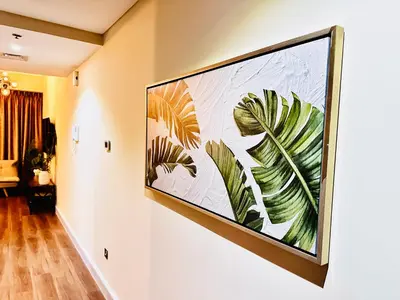 a large painting of leaves on a wall at Prime Modern Downtown Studio - Boulevard View in Dubai