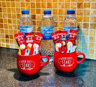 two cups filled with toothbrushes and two bottles of water at Prime Modern Downtown Studio - Boulevard View in Dubai