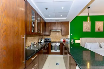 a kitchen with wooden cabinets and a green wall at Prime Modern Downtown Studio - Boulevard View in Dubai