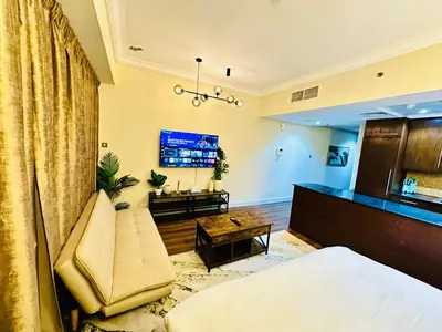 a living room with a couch and a tv at Prime Modern Downtown Studio - Boulevard View in Dubai