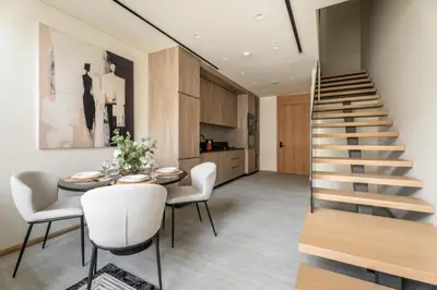 a staircase in a living room with a table and chairs at GuestReady | Stylish 1BR Penthouse Retreat in Dubai
