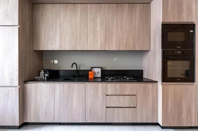 a kitchen with wooden cabinets and a sink and a microwave at GuestReady | Stylish 1BR Penthouse Retreat in Dubai