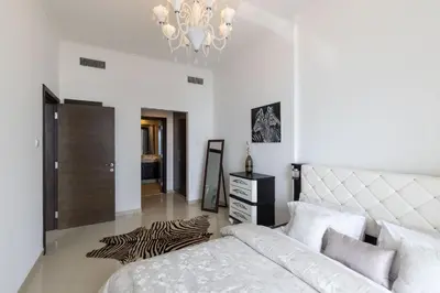 a white bedroom with a bed and a chandelier at VayK - Amazing 1BR in Marina with Sea View in Dubai