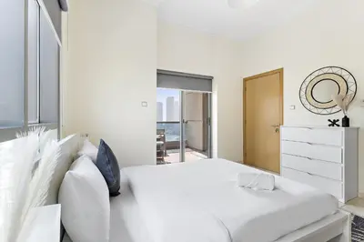 a white bedroom with a large bed and a mirror at VayK - Modern and Central 1BR in the Marina in Dubai