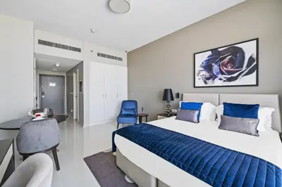 a bedroom with a bed and a desk and a chair at VayK - Chic Hotel Style Studio in Damac Hills in Dubai