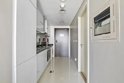 a white kitchen with a sink and a microwave at VayK - Chic Hotel Style Studio in Damac Hills in Dubai