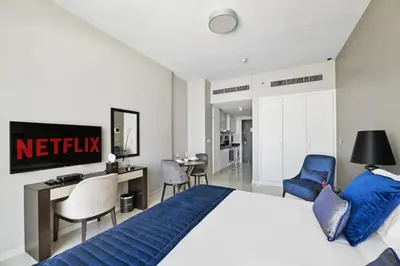 a bedroom with a bed and a desk and chairs at VayK - Chic Hotel Style Studio in Damac Hills in Dubai