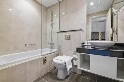 a bathroom with a toilet and a sink and a bath tub at VayK - Chic Hotel Style Studio in Damac Hills in Dubai