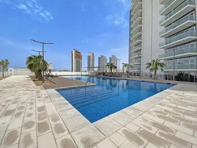 a swimming pool with palm trees and a building at VayK - Chic Hotel Style Studio in Damac Hills in Dubai