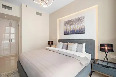 a white bedroom with a large bed and a painting at VayK - Renovated 1BR in Dubai Marina in Dubai