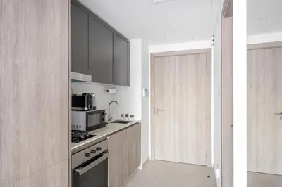 a kitchen with black and white cabinets and a door at VayK - Cozy Studio with a Balcony & Pool Views in Dubai
