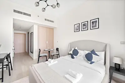 a white bedroom with a bed and a dining room at VayK - Modern Studio in Prime Meydan Area in Dubai