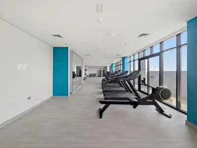 a gym with rows of tread machines and windows at VayK - Modern Studio in Prime Meydan Area in Dubai
