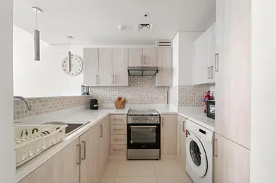a kitchen with white cabinets and a washer and dryer at VayK - Great 1BR with Beach Access in Dubai