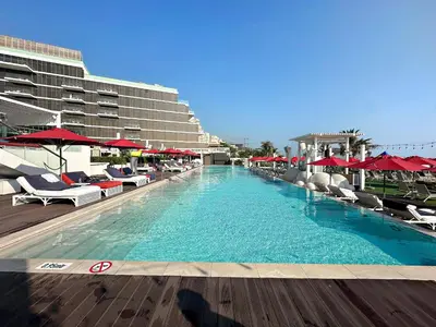 a large swimming pool with chairs and red umbrellas at Upscale 1BR with Beach Access on Palm Jumeirah in Dubai