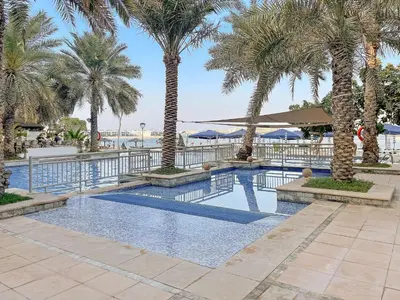 a swimming pool with palm trees in a resort at VayK - Beachfront 1BR on Palm Jumeirah with Sea View in Dubai