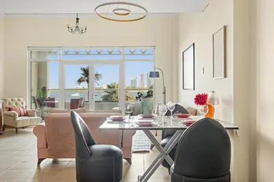 a dining room with a table and chairs and a living room at VayK - Beachfront 1BR on Palm Jumeirah with Sea View in Dubai