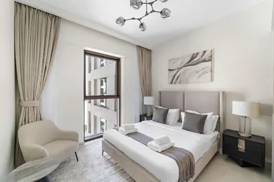 a white bedroom with a large bed and a chair at VayK - Modern 1BR Getaway in Creek Harbour in Dubai