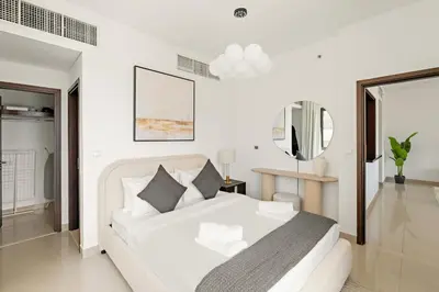 a white bedroom with a white bed and a mirror at VayK - Modern 1BR in Downtown Dubai in Dubai