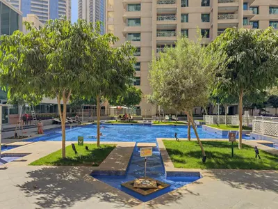 a swimming pool with trees and a building in the background at VayK - Modern 1BR in Downtown Dubai in Dubai