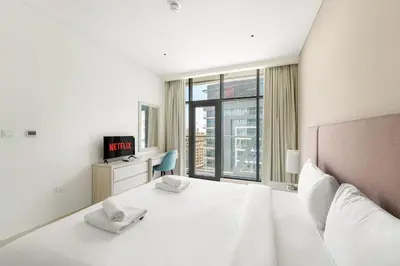 a white bedroom with a bed and a window at VayK - Modern 1BR on Palm Jumeirah in Dubai
