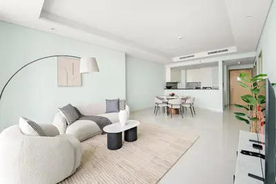 a white living room with a couch and a table at VayK - Spacious 2BR Inside Hotel in Dubai