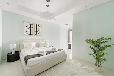 a white bedroom with a bed and a potted plant at VayK - Spacious 2BR Inside Hotel in Dubai