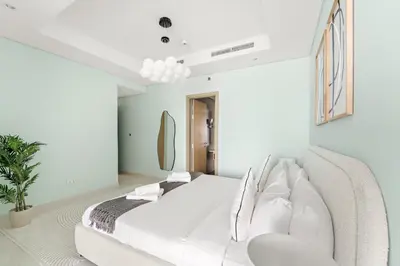 a white bedroom with a white bed and a couch at VayK - Spacious 2BR Inside Hotel in Dubai