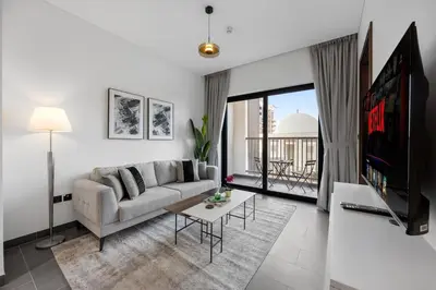 a living room with a couch and a tv at Modern 1BR Apartment with Balcony in Sobha Hartland in Dubai