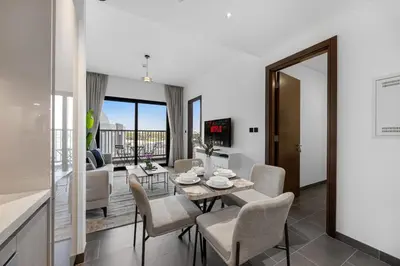 a dining room and living room with a table and chairs at Modern 1BR Apartment with Balcony in Sobha Hartland in Dubai