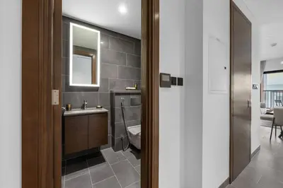 a bathroom with a sink and a toilet and a mirror at Modern 1BR Apartment with Balcony in Sobha Hartland in Dubai