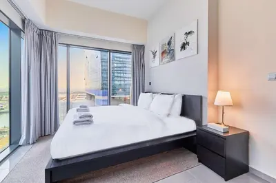 a bedroom with a large bed and a large window at Home Away 2BR in Dubai