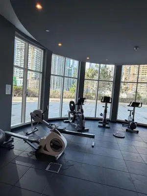 a gym with treadmills and ellipticals in a room with windows at Prime location cozy apartment in Dubai