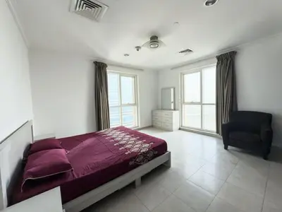 a bedroom with a bed and a chair and windows at Prime location cozy apartment in Dubai