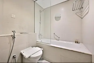 a white bathroom with a toilet and a bath tub at Luxury 2BDR In Burj Khalifa View Business Bay in Dubai