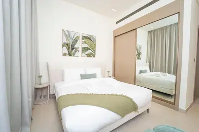 a white bedroom with a large bed and a mirror at AWS Holiday Homes - Stay in Style in Dubai