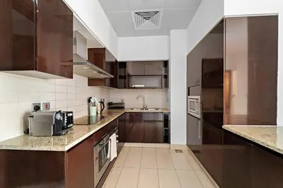 a large kitchen with brown cabinets and a sink at VayK - Spacious 2BR with Private Gym & Beach Access in Dubai
