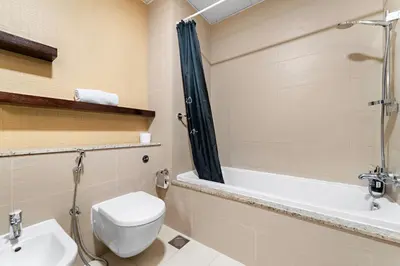 a bathroom with a toilet and a sink and a bath tub at VayK - Spacious 2BR with Private Gym & Beach Access in Dubai