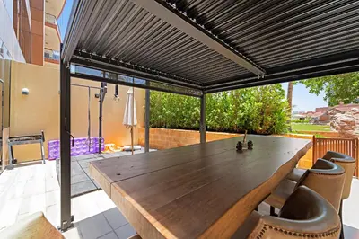 a wooden table and chairs on a patio at VayK - Spacious 2BR with Private Gym & Beach Access in Dubai