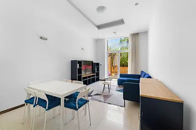 a living room with a white table and blue chairs at VayK - Spacious 2BR with Private Gym & Beach Access in Dubai