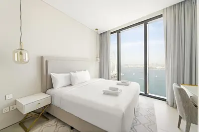 a white bedroom with a large bed and a large window at VayK - Luxurious 2BR Beachfront Retreat with Ocean View in Dubai
