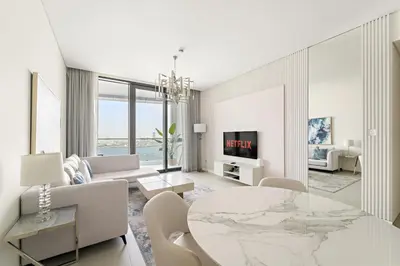 a white living room with a table and a couch at VayK - Luxurious 2BR Beachfront Retreat with Ocean View in Dubai