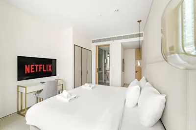 a white hotel room with a bed and a tv at VayK - Luxurious 2BR Beachfront Retreat with Ocean View in Dubai